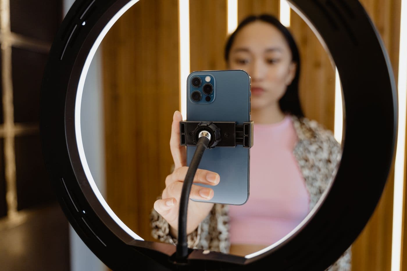 Perempuan merekam diri dengan ponsel yang terpasang di tengah ring light menyala